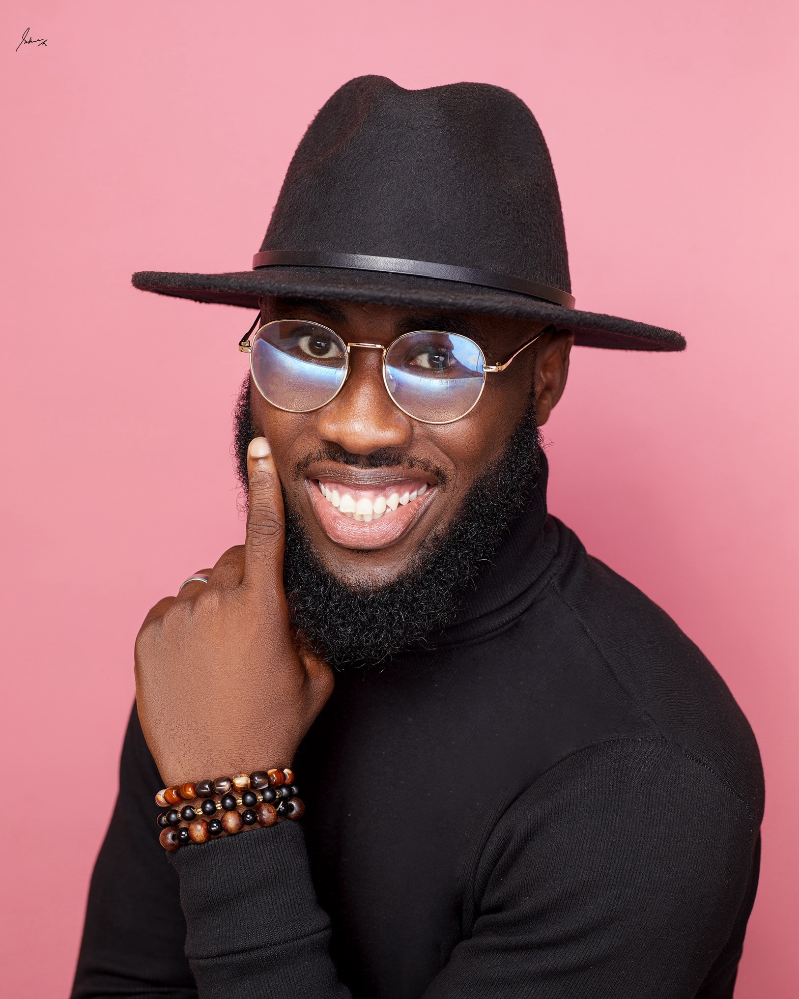 Portrait of Ojobo Agbo Eje smiling against a pink background